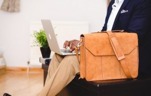 Man typing on a laptop with a business suit case